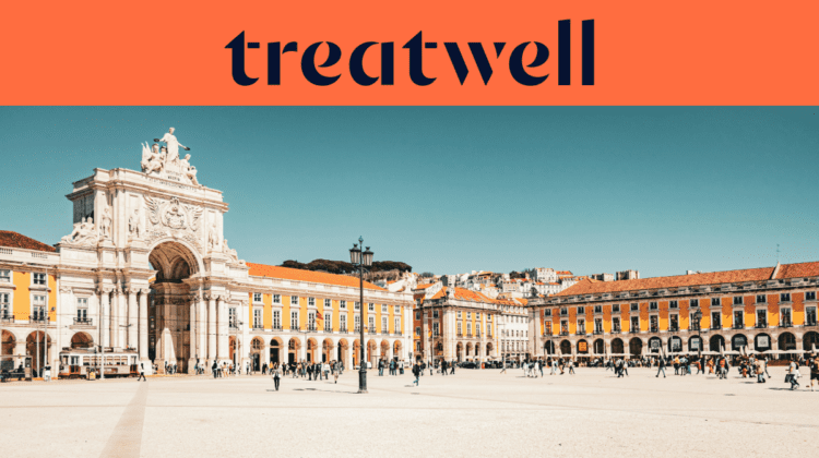 Platus baneris su tamsiai mėlynu Treatwell logotipu ant oranžinio fono vir&scaron;uje. Žemiau logotipo – ry&scaron;ki, saulėta Lisabonos Komercijos aik&scaron;tės (Praça do Comércio) nuotrauka: baltoji Rua Augusta arka, geltoni pastatai su arkinėmis kolonadomis ir žmonės, vaik&scaron;tantys per plačiąją pėsčiųjų aik&scaron;tę po giedru mėlynu dangumi.