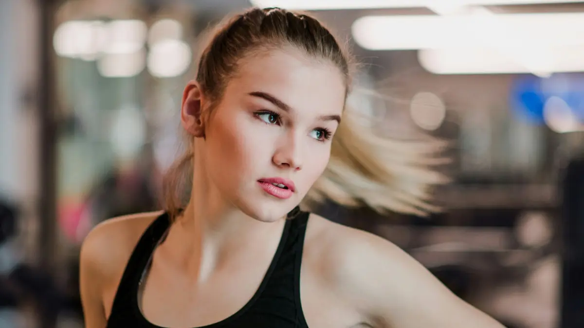 Jauna moteris sportine palaidine juda į šoną, o jos surinkti plaukai skrieja į išorę