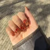 „Lava nails“ nagų dailė su gintariniais ir raudonais sūkuriais ant permatomo pagrindo