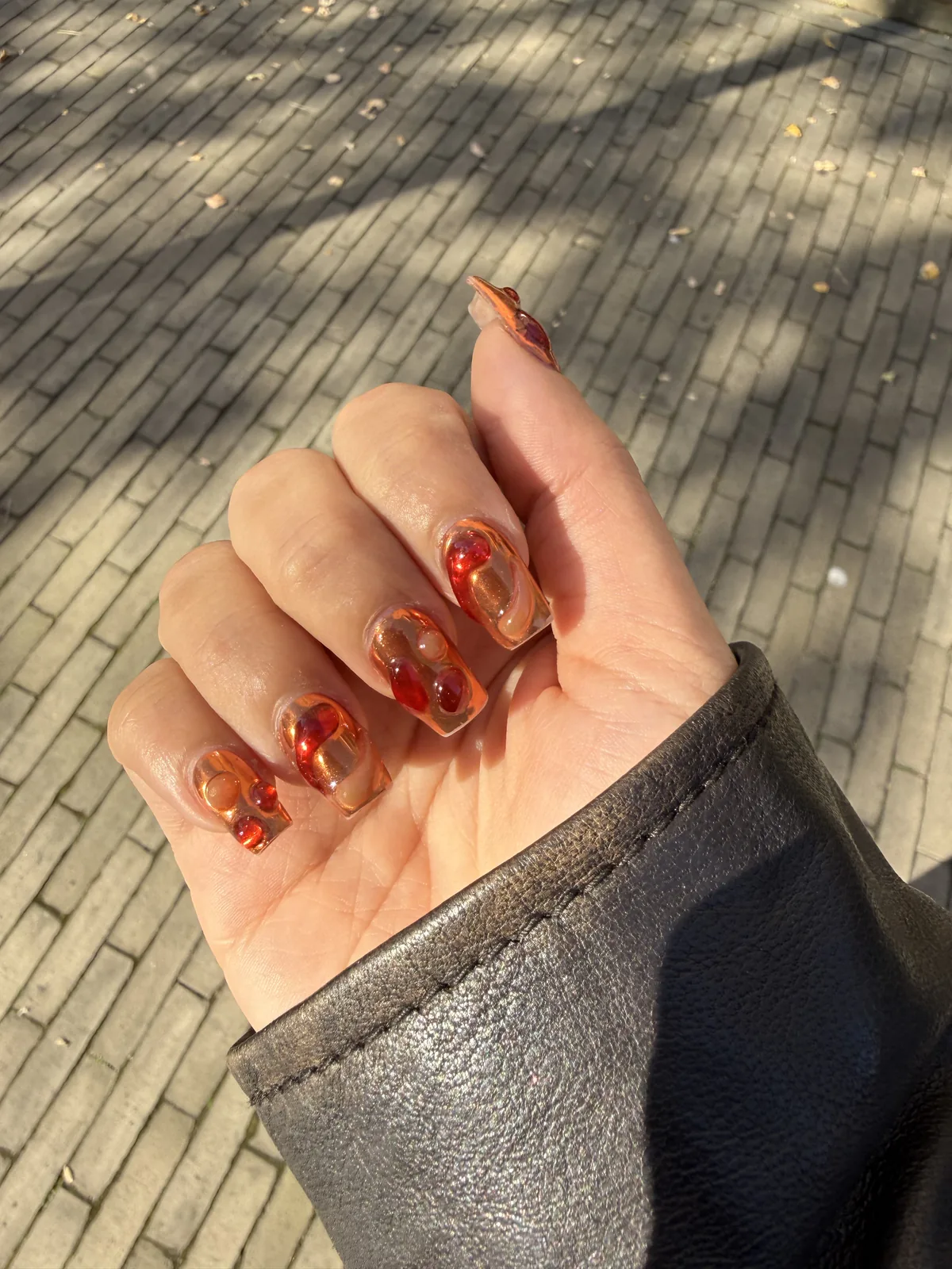 „Lava nails“ nagų dailė su gintariniais ir raudonais sūkuriais ant permatomo pagrindo